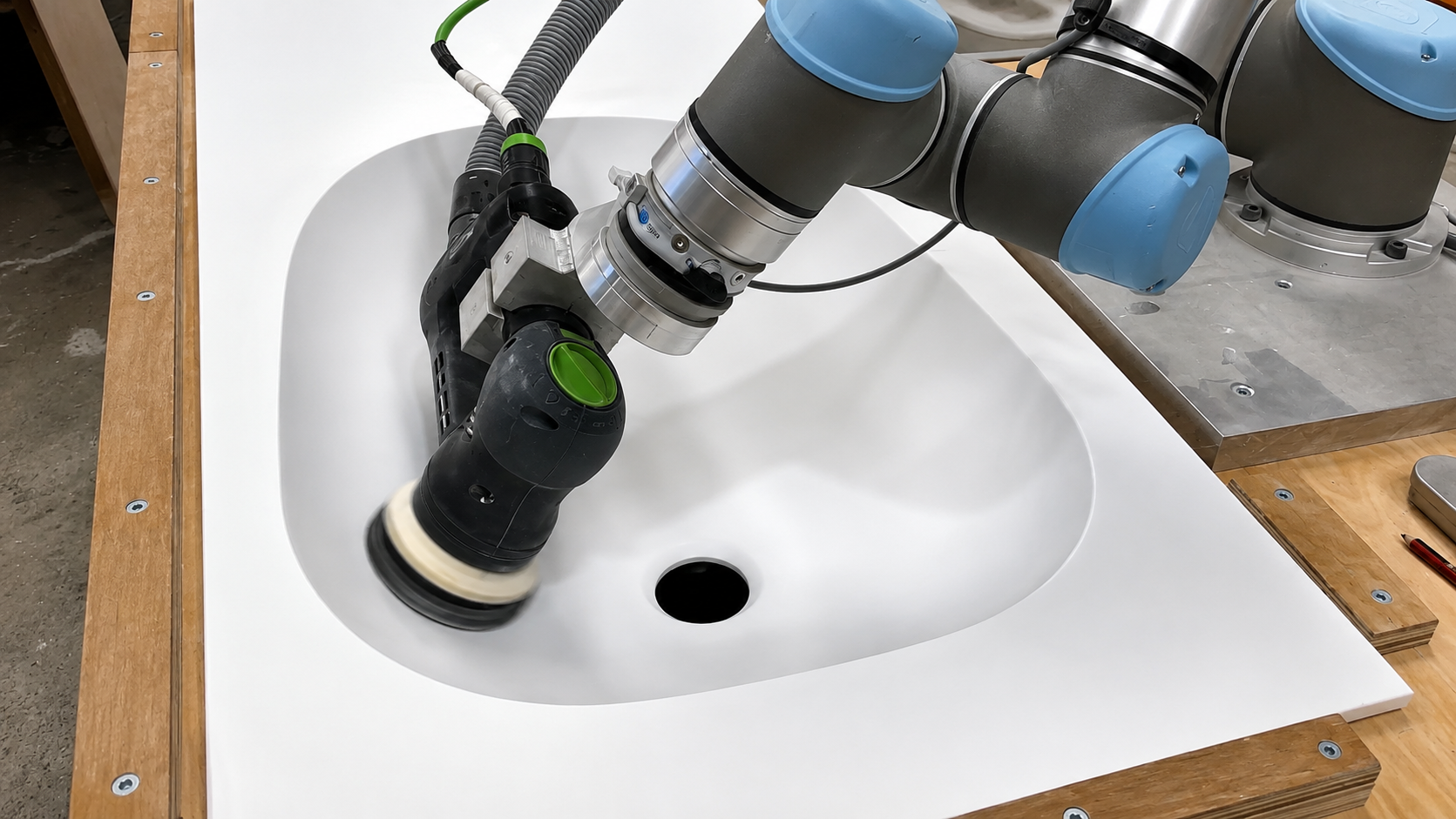 Cobot sanding a moulded basin with an orbital sander