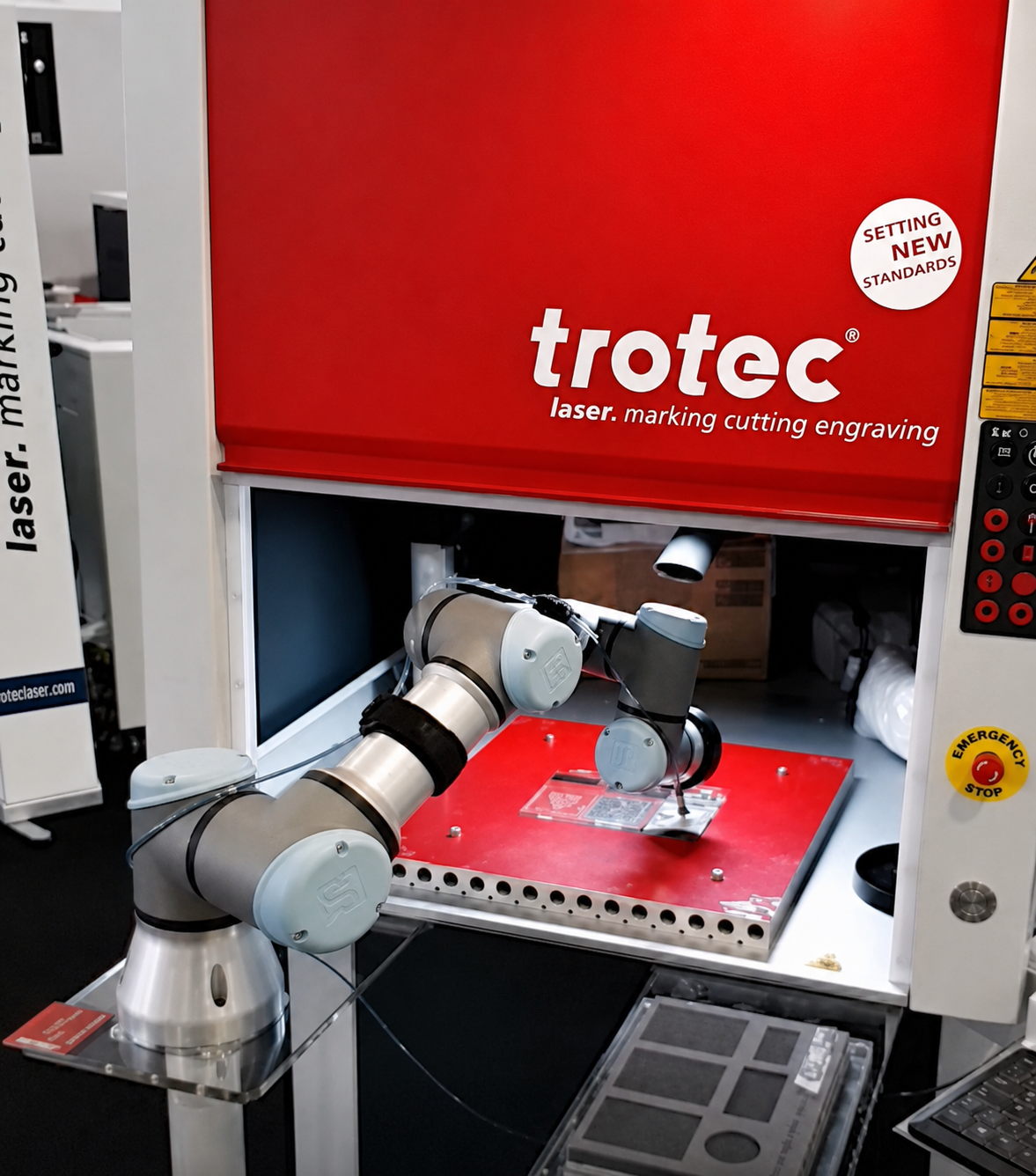 Cobot loading parts into a Trotec laser marking machine